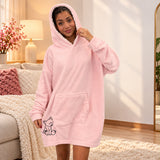 Woman in a pale pink fleece hooded blanket with the hood up and a bear outline near the hem