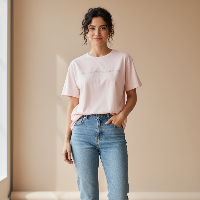 Woman wearing a light pink tshirt on a dark beige surface