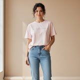 Woman wearing a light pink tshirt on a dark beige surface