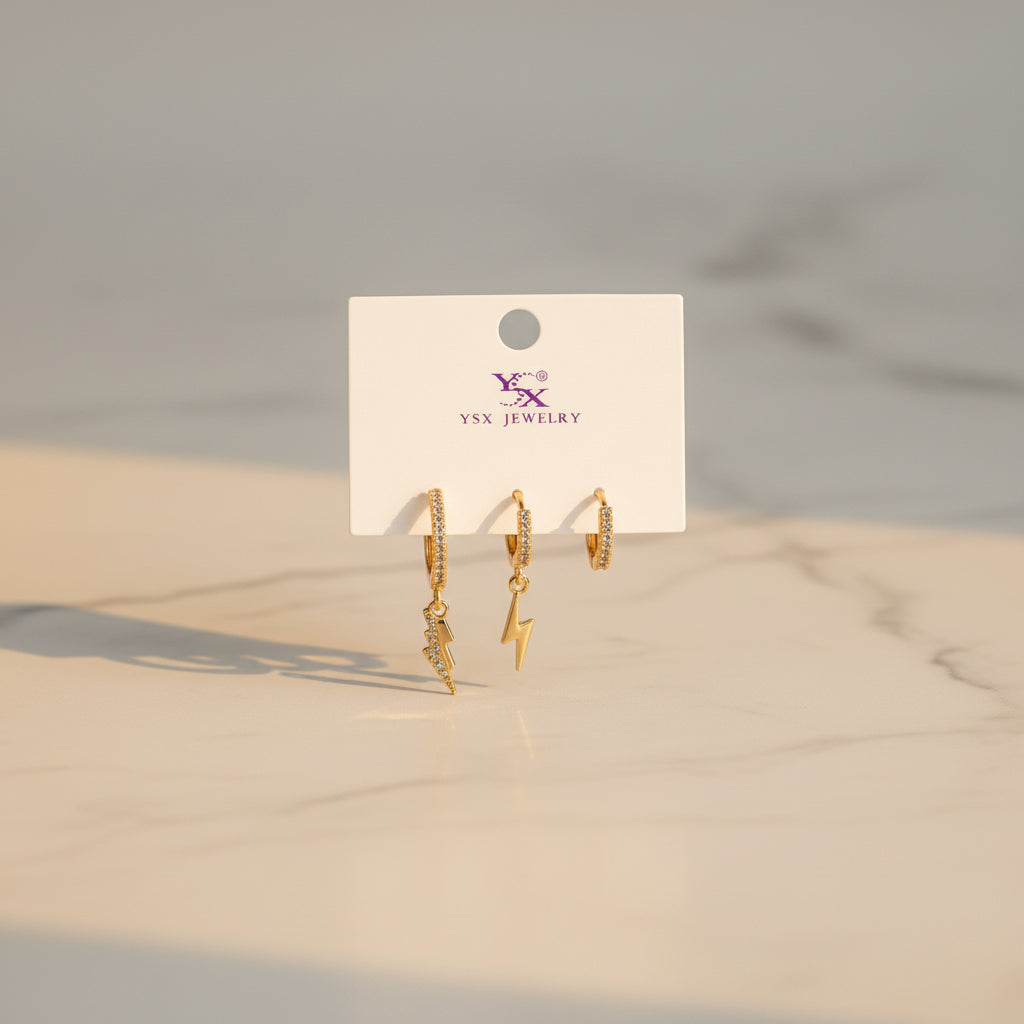 Gold lightning earrings on a Jewelry card against a neutral background