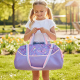 Girl holding a lilac kids duffle bag with a butterfly print panel and pastel striped handles