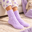 Child wearing lilac cable knit fuzzy socks on a cream rug with heart print pyjama cuffs