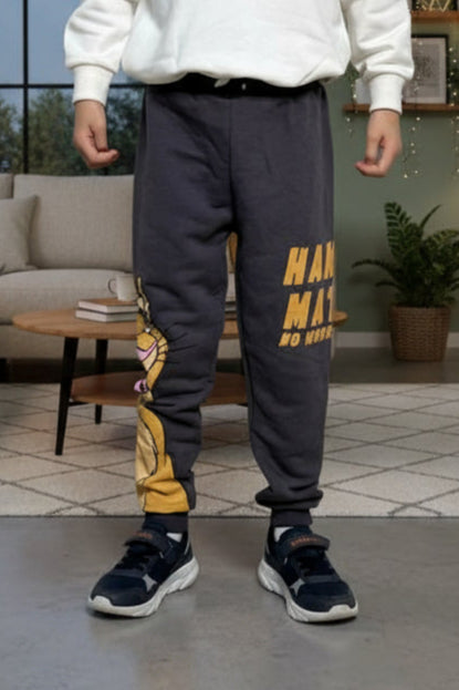 Boy wearing charcoal grey lion cub joggers with gold Hakuna Matata lettering in a living room