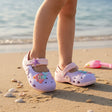Girls lilac clog sandals with mermaid and starfish charms worn on the beach