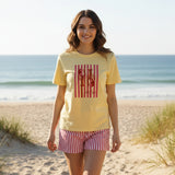 Yellow t-shirt with red graphic and red striped shorts on a dark surface