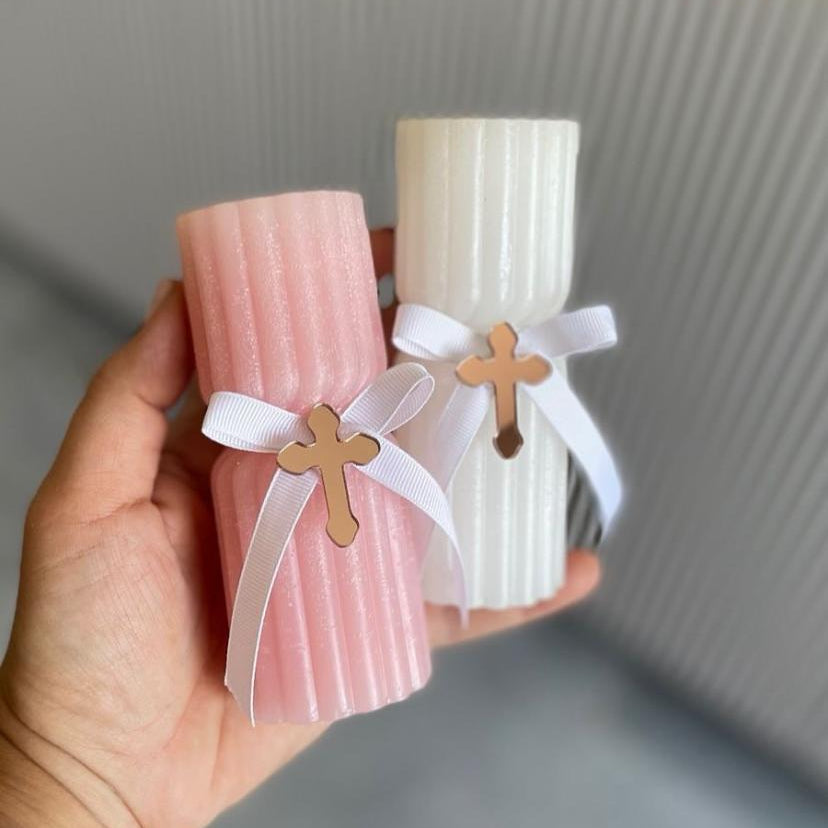 Fluted blush and ivory pillar candles tied with white ribbon and a rose gold cross