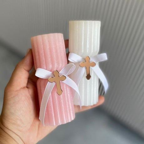 Fluted blush and ivory pillar candles tied with white ribbon and a rose gold cross
