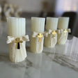 Four ivory fluted candles with lace ribbon and plain gold crosses on white marble