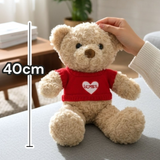 Adult hand resting on a cream jumper bear seated on a grey living room ottoman