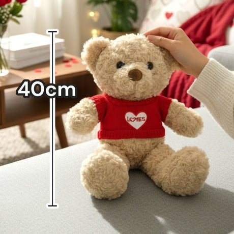 Cream curly bear in a red knit jumper with a white heart, on a bed dressed with roses