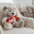 Taupe teddy bear in a red satin bow holding a padded red heart, with a 50cm line