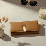 Havan wallet with gold clasp on a light surface with sunglasses and a candle
