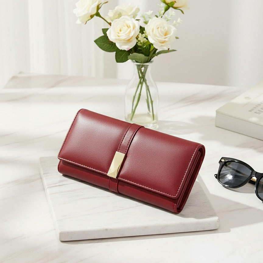 Red wallet on a white surface with flowers and sunglasses in the background