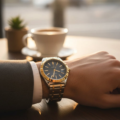Luxury gold wristwatch on a person's hand with a blurred coffee cup and plant in the background
