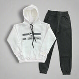 White hoodie with a football badge print laid out with charcoal joggers