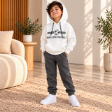 Boy in a white Man I Love Football hoodie and dark grey joggers in a living room