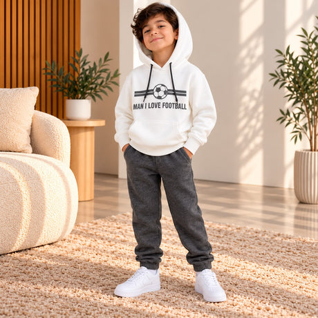 Boy in a white Man I Love Football hoodie and dark grey joggers in a living room