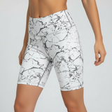 White athletic shorts with black abstract pattern worn by a person on a light grey background