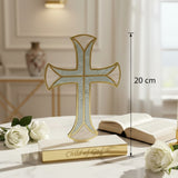 Pale blue pearlised cross on a marble table beside an open book and white roses