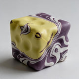 Purple and yellow marbled cube squishy with swirled dimpled sides