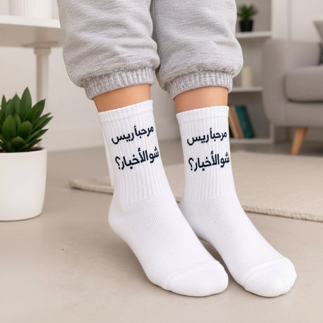 White crew socks with a navy Arabic greeting printed across the ribbed cuff