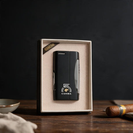 Slim matte black cigar lighter with a printed emblem in a cream gift box next to a cigar