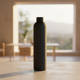 Matte black 1L water flask on a stone counter in golden light