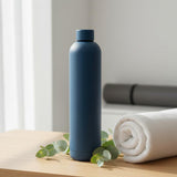Slate blue matte 1L water flask beside a rolled yoga mat and towel