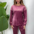 Woman in a mauve pink velvet PJ set with a Be The Sunshine print top and matching pants