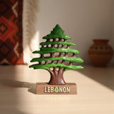 Bright green cedar tree statue with a red brown trunk on a wooden Lebanon base