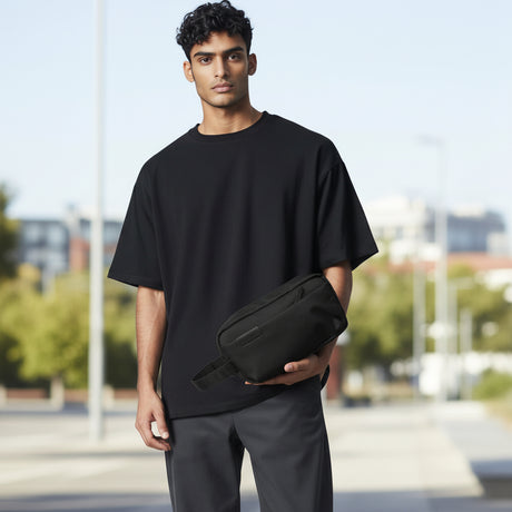 Man holding a black pouch outdoors with blurred background
