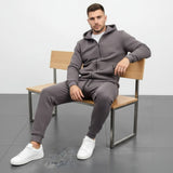 Man sitting on a bench wearing a grey tracksuit and white sneakers