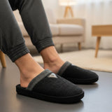 Black slippers worn indoors with a blurred background