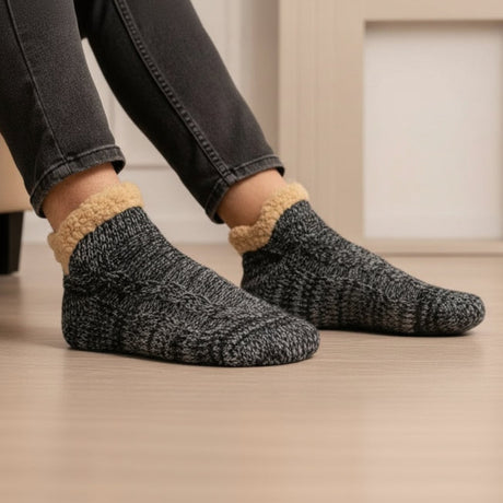 Person wearing grey socks with beige trim on a wooden floor