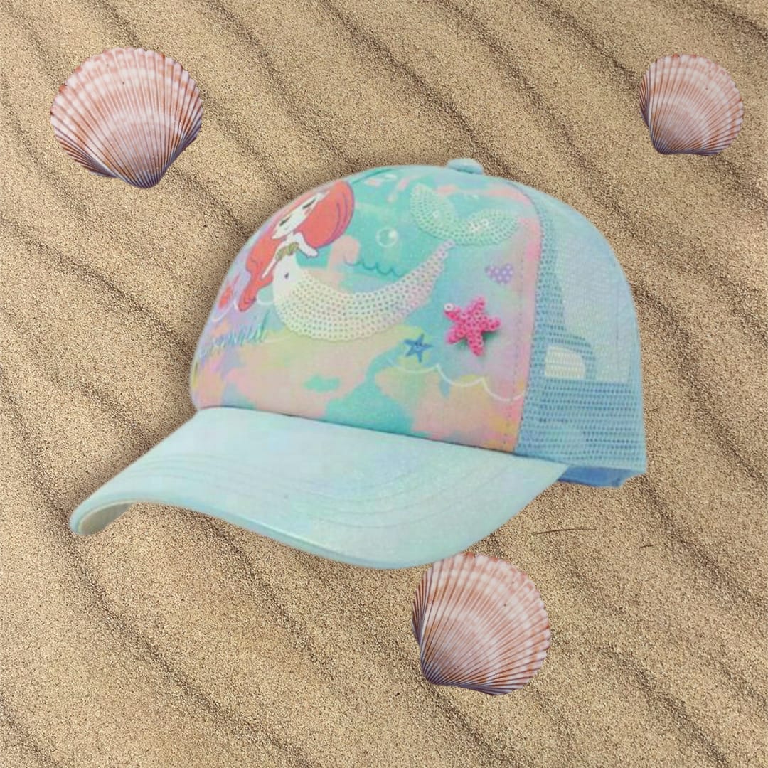 Mint kids cap with a mermaid print, sequin tail and pink starfish patch resting on sand