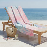 Pink and aqua mermaid tail towel draped over a wooden lounger by the sea