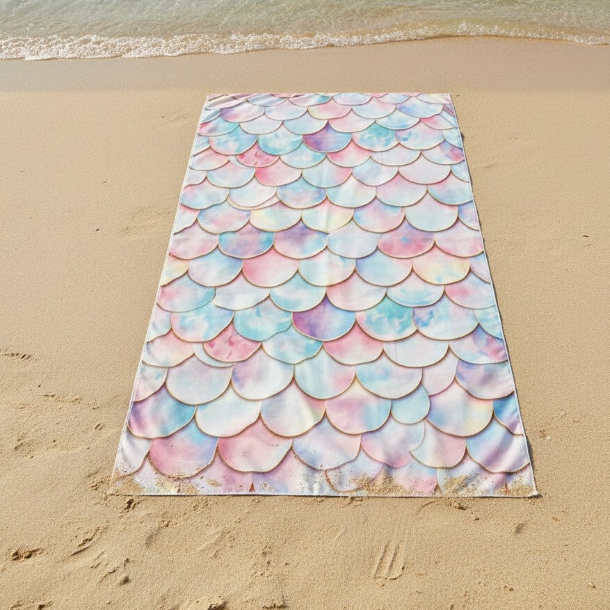 Beach towel with mermaid scale pattern on a sandy beach