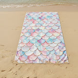 Beach towel with mermaid scale pattern on a sandy beach