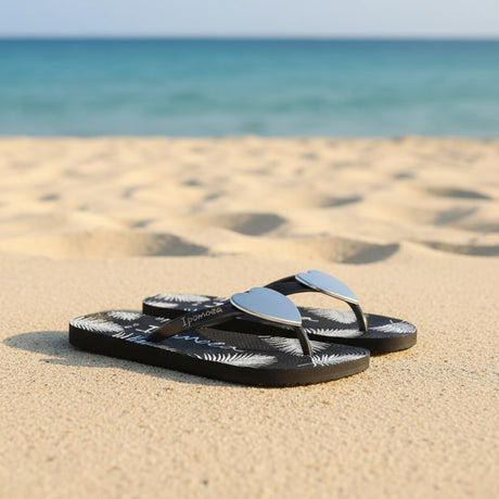 Black thong flip flops with a chrome heart on the toe post and white fern fronds on the footbed