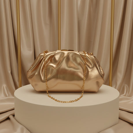Gold metallic pleated pouch clutch with a chain strap on a plinth