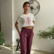 Cream crop tee with a pink milkshake doodle, worn with burgundy trousers