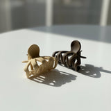 Beige and brown mini claw clips on a white table in soft daylight