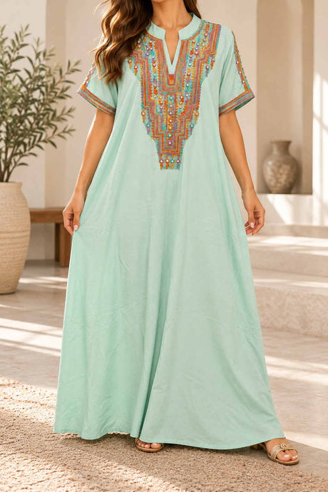 Woman in a mint green maxi kaftan with a colourful embroidered neckline and short sleeves