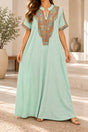 Woman in a mint green maxi kaftan with a colourful embroidered neckline and short sleeves