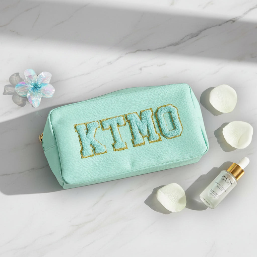 Mint pouch with 'KTMO' text on a marble surface with skincare products