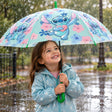 Little girl in a floral jacket under a mint umbrella with a stitch hugging a heart