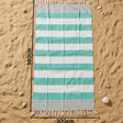 Teal and white striped towel on sand with measurement indicators