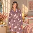 Woman in a mocha fleece robe with large blush pink dots, belted at the waist