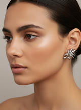 Close-up of a woman wearing a silver modern earring with a neutral background