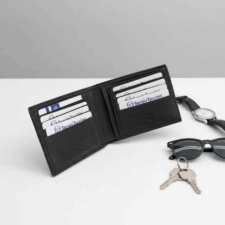 Black wallet with cards, keys, sunglasses, and watch on a white surface